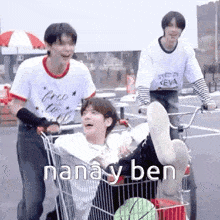 a group of young men are pushing a shopping cart with a person laying in it .