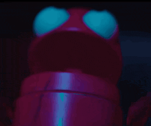 a close up of a red object with blue eyes in the dark