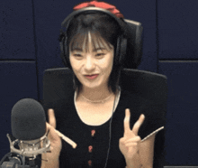 a woman wearing headphones is giving the peace sign