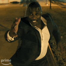 a man in a suit and white shirt is waving his hand in front of a prime logo