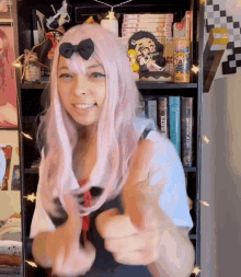 a woman wearing a pink wig is giving a thumbs up