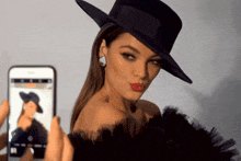 a woman wearing a black hat is being photographed by a phone