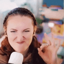 a woman is making a funny face and giving an okay sign