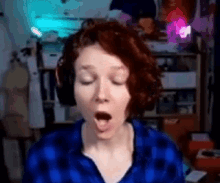a woman wearing headphones and a plaid shirt is yawning .