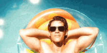 a shirtless man wearing sunglasses is laying on a raft in the water