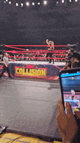 a person taking a picture of a wrestling match with a sign that says new collision