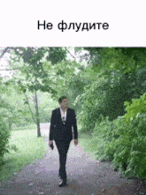 a man in a suit is walking down a path in the park