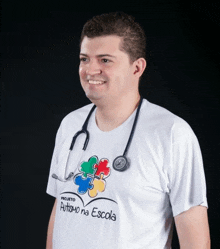 a man with a stethoscope around his neck is wearing a shirt that says " autismo na escola "