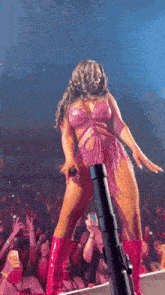 a woman is standing on a stage holding a microphone in front of a crowd of people .