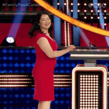a woman in a red dress is standing on a stage in front of a podium .