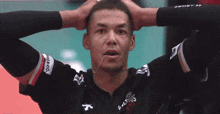 a man with a string in his mouth is wearing a black shirt with the word suites on it .