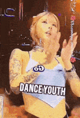 a woman with tattoos on her arms is wearing a blue top that says danceyouth