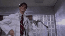 a man in a lab coat and tie is using a stethoscope in a room .