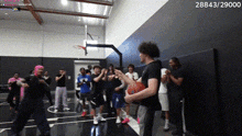 a group of people are standing around a basketball court watching a man shoot a basketball .