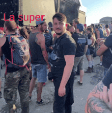 a man in a black shirt stands in a crowd of people with the words la super written in red