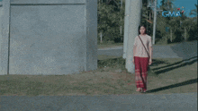 a woman walking down a street with a gma logo on the bottom