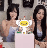 two women are sitting at a table with a cake in front of them