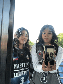 a girl wearing a maritim longevity jersey takes a selfie with another girl