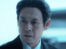 a man in a suit and tie looks at the camera with a serious look on his face