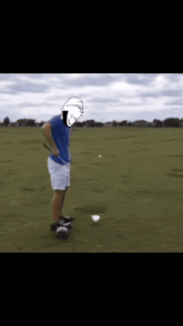 a man in a blue shirt is standing on a golf course