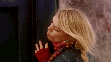 a woman wearing a red scarf and a denim jacket is standing in front of a door