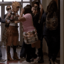 a group of people standing in a hallway including a woman wearing a pink shirt