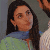 a woman in a green dress looks at a man in a striped shirt