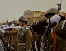 a group of soldiers salute in front of a building that says ' metropol ' on it