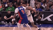 a basketball player with the number 9 on his jersey is fighting another player