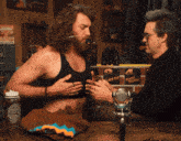 two men are sitting at a table with a sign that says 24