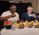 two men are sitting at a table with a coffee pot that says french roast coffee