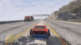 a red car is driving down a highway next to a semi truck .