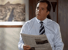a man in a white shirt and tie is holding a newspaper that says ' cidade ' on it