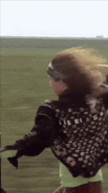 a girl wearing a headband and a bomber jacket is holding a gun