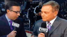 a man in a suit and tie talking into a yes microphone