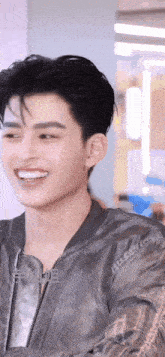 a close up of a young man wearing a grey jacket and smiling