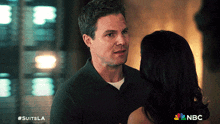 a man and a woman are looking at each other with a nbc logo in the background