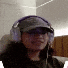 a woman wearing headphones and a hat is smiling for the camera .