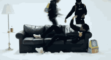 a man is laying on a couch in the snow while another man stands behind him