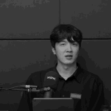a man stands in front of a microphone that says now