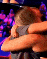 a woman is hugging a man in front of a crowd .