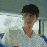 a young man wearing glasses and a white shirt is sitting on a bus .