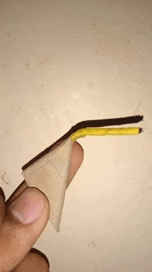 a person is holding a yellow straw and a piece of paper in their hand .