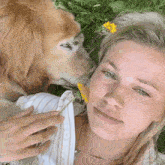 a woman laying in the grass with a dog and a flower in her hair