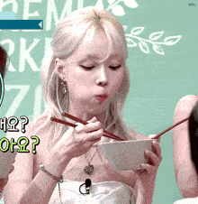 a woman eating from a bowl with chopsticks with bite written on the bottom right