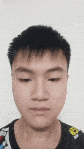 a close up of a young man 's face with a black shirt with a yellow letter g on it