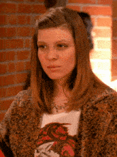a woman wearing a leopard print coat and a t-shirt with a dragon on it is looking at the camera