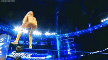 a woman is falling through the air in a wrestling ring while a man looks on .