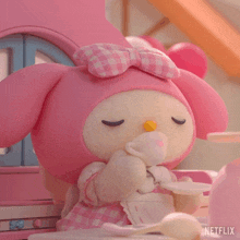 a stuffed animal is sitting at a table with a cup and saucer and a netflix logo in the corner