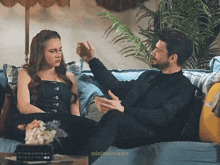 a man and a woman are sitting on a couch with minimalmoons in the corner